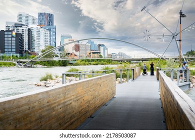 Calgary Alberta Canada, July 02 2022: People Walking Across A Pathway Through St. Patricks Island With Public Art Displays And Downtown City Skyline.