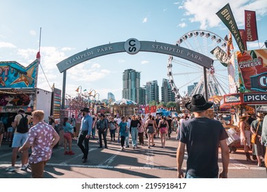 Calgary, Alberta, Canada - July 16, 2022: Crowds Of People Enter Stampede Park, The Midway Carnival Rides And Games Area