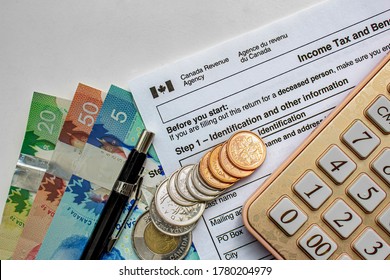 Calgary, Alberta, Canada. July 20, 2020. Canadian Tax Forms With Coins, Calculator, A Pen And Bills On A White Table. Tax Time Concept