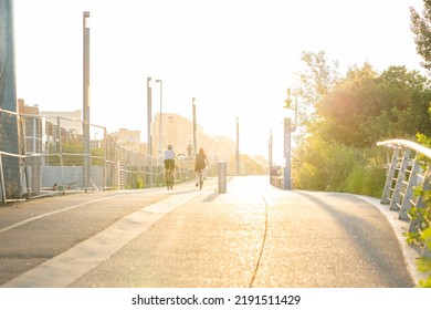 Calgary Alberta Canada, July 27 2022: Two People Riding Bikes Along A Pedestrian Pathway With Construction Fencing For Flood Mitigation Near The Downtown East Village.