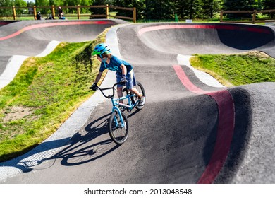 Calgary Alberta Canada, June 20 2021: A young child rides the new South Glenmore Park BMX pump track on his bike on a summer evening in Calgary Alberta Canada.