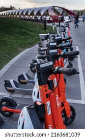 Calgary Alberta Canada, May 22 2022: Electric Scooters For Rent Lined Up In A Designated Parking Spot Along A Popular Downtown Bike Path Near The Santiago Peace Bridge.