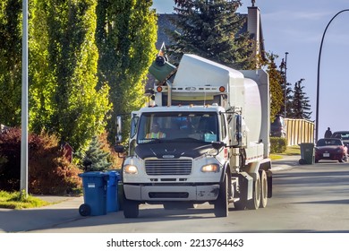 Calgary, Alberta, Canada. Oct 13, 2022. A Garbage Truck Taking A Green Cart Food And Yard Waste.