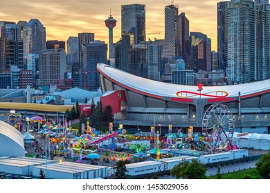 CALGARY, CANADA - JULY 14, 2019: Sunset over Calgary skyline with the annual Stampede event at the Saddledome grounds. The Calgary Stampede is renowned as the greatest outdoor show on Earth.