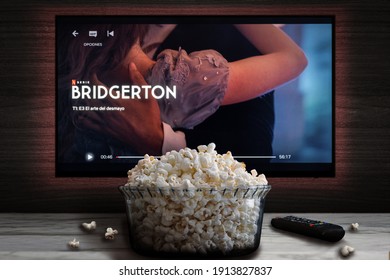 Cali, Colombia - February 9 2021: Netflix app on tv screen playing "Bridgerton" behind a bowl of popcorn and a remote control.
