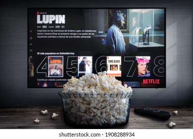 Cali, Colombia - January 27, 2021: Netflix app on tv screen playing "Lupin"  behind a bowl of popcorn and a remote control.