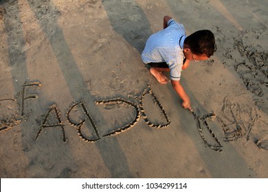 CALICUT, INDIA - FEB 10 : Unidentified kid writes letters on the sand at the beach on February 10, 2018 in Calicut, Kerala,India.