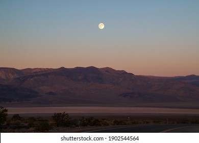 California Desert With Full Moon At Early Morning Right Before Sunrise, Road Trip Through Typical Southwest American Desert, Death Valley Mountains, USA

