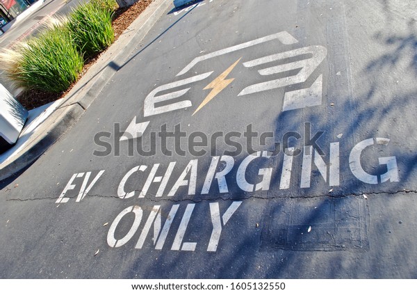 California, USA - 2019: Electronic Vehicle\
charging station parking spot. Paint on asphalt. EV charging only 2\
hour limit. Also called EV charging station, electric recharging\
point, charge\
point.