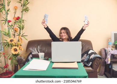 A call for a celebration after a making money from her side hustle. A female freelancer makes money online, showing dollar bills. - Shutterstock ID 2185346769