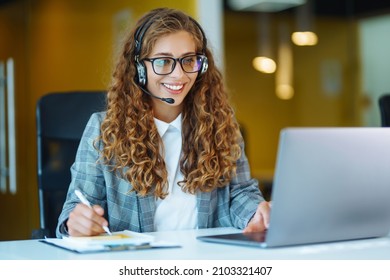 Call center agent with headset working on support hotline in modern office. Video conference.  Оnline training. - Shutterstock ID 2103321407