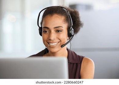 Call center agent with headset working on support hotline in office. Black businesswoman in conversation with customer during video call. African american business woman working remotely on laptop. - Powered by Shutterstock