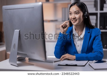 Call center agent with headset working on support hotline in modern office with copy space. Portrait of asian woman agent in conversation with customer over headset at workplace