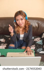 A Call Center Agent Working Remotely At Home Giving A Thumbs Up Gesture. Satisfied About Her Job Performance And Company Perks.