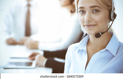 Call center and business people concept. Beautiful business woman with headphones consulting clients. Group of diverse phone operators at work in office