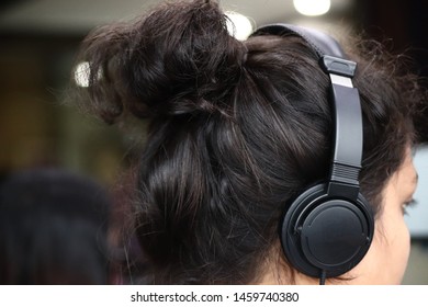 Call center business woman talking on headset. Young woman listening to music via headphones. Headphones allow you to listen to audio or watch a movie without disturbing people around you. - Shutterstock ID 1459740380