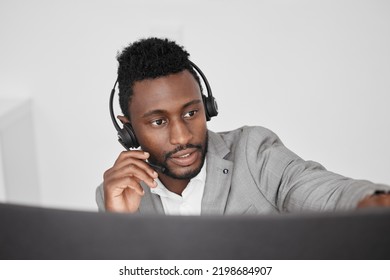 Call Center, Customer Service And Crm Representative Wearing Headset While Consulting With Customer In Telemarketing Company. Serious Black Man In Contact Us And Sales Support Working On A Computer