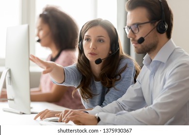 Call center employees wearing headset using computer, woman explains show to new colleague marketing database program, busy service phone operators sitting at shared desk, assistance teamwork concept - Shutterstock ID 1375930367