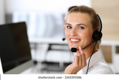 Call center. Happy and excited business woman using headset while consulting clients online. Customer service office or telemarketing department. Smiling group of operators at work - Shutterstock ID 1543393586