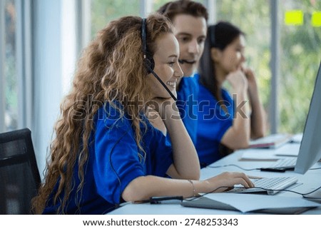 Call center representative using desktop computer and headset to provide online assistance in bright contemporary workspace, emphasizing communication, teamwork and professional customer service.