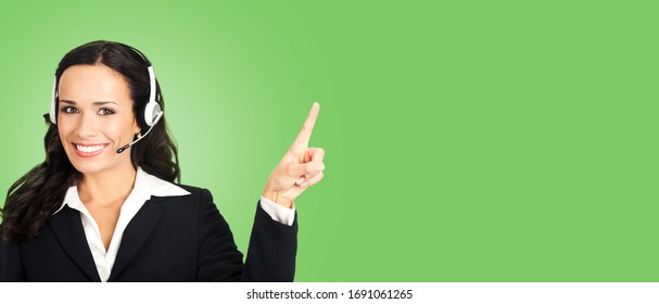 Call center service. Customer support female phone sales operator in headset showing something or copy space for some text, imaginary, product or slogan, on green color background.
