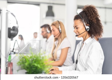 Call Center Worker Accompanied By Her Team. Smiling Customer Support Operator At Work. Young Employee Working With A Headset.