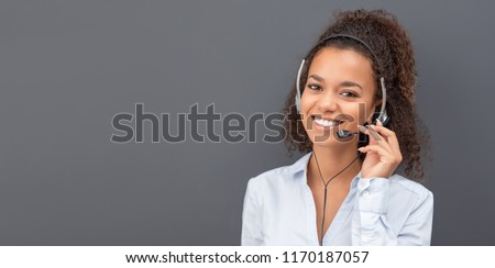 Call center worker isolated on a gray background. Smiling customer support operator at work. Young employee working with a headset.