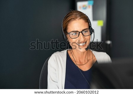 Call centre operator with headset on support hotline working from home. Mature positive agent in conversation with customer over headset. Happy middle aged businesswoman talking in a conference call.