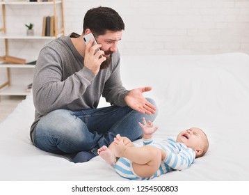 Call For Help. Young Father Upset At Crying Baby, Talking On Phone With Wife, Copy Space