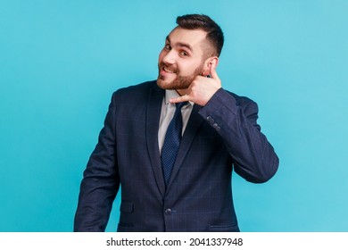 Call Me! Portrait Of Handsome Cheerful Man With Beard In Suit Holding Telephone Hand Gesture Near Ear, Imitating Communication On Phone. Indoor Studio Shot Isolated On Blue Background.