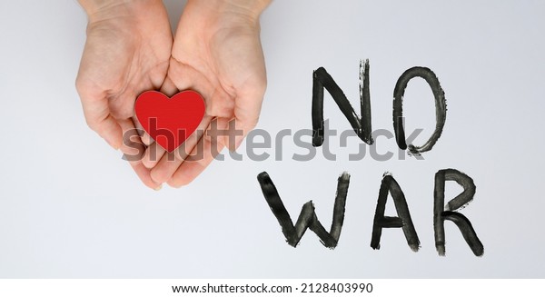 A call for peace\
and an end to the war. Red heart in female hands next to the black\
inscription No war.