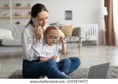 Call to pediatrician. Stressed mother talking to doctor, worried about her son's health, checking child's temperature by holding hand on kid forehead. Remote healthcare consultation.