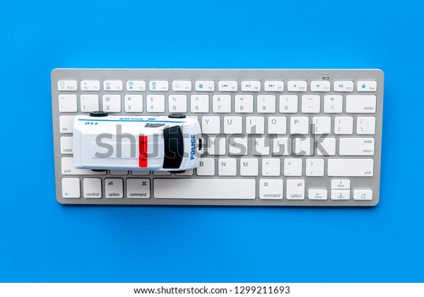 Call police online concept. Police\
car toy and computer keyboard on blue background top\
view