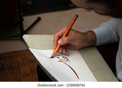 A calligrapher writing with pen and ink. man hands writing arabic calligraphy with ink. Arabic and Persian calligraphy. Writing Nastaliq calligraphy. Abstract and unclear writing.