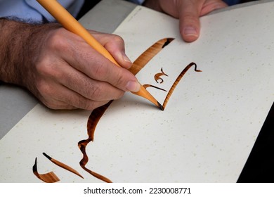 A calligrapher writing with pen and ink. man hands writing arabic calligraphy with ink. Arabic and Persian calligraphy. Writing Nastaliq calligraphy. 