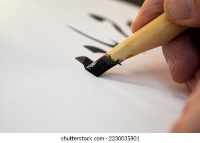 A calligrapher writing with pen and ink. man hands writing arabic calligraphy with ink. Arabic and Persian calligraphy. Writing Nastaliq calligraphy. Calligraphy training. Close-up of Arabic reed pen