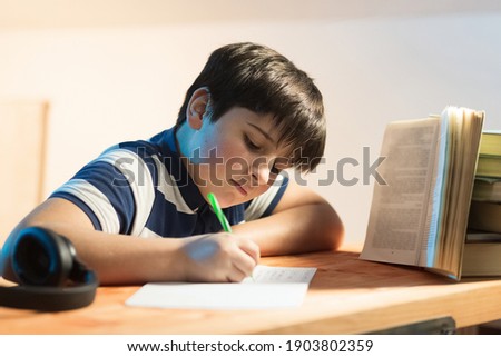 Calligraphy classes. boy in front of a book while busy rewriting text
