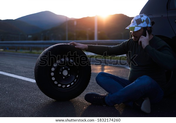 Calling car service, assistance or  tow truck\
while having troubles with his car. Man calling road assistance on\
the highway.