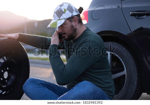 Calling car service, assistance or  tow truck
while having troubles with his car. Man calling road assistance on
the highway.