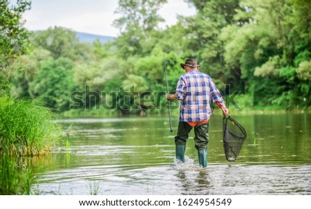 Calling Fly-Fishing a hobby. fisherman with fishing rod. retired bearded fisher. Trout bait. hobby and sport activity. mature man fly fishing. man catching fish. summer weekend. Big game fishing.