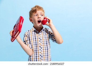 Calling In The Past. Cute Preschool Boy, Kid Wearing Retro Style Outfit Using Retro Phone Isolated On Light Blue Background. Concept Of Child Emotions, Facial Expression, Fashion And Ad.