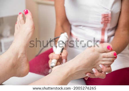 Callus peeling using professional pedicure drill machine. Spa foot treatment. Removing hard, callused skin for soft feet. High quality photo.