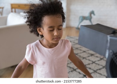 Calm African American Little Kid Girl Feeling Hot, Standing At Fresh Cool Air Blowing From Fan. Home Alone Child With Closed Eyes Enjoying Freshness From Electric Blower, Ventilator, Cooler