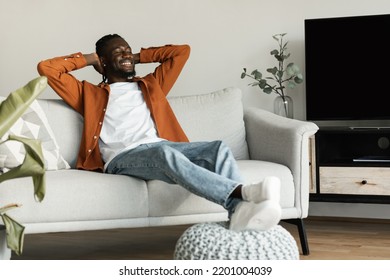 Calm African American Man Relaxing On Couch With Hands Behind Heads At Home, Copy Space. Carefree Black Guy Chilling On Sofa, Enjoying Peaceful Weekend Morning