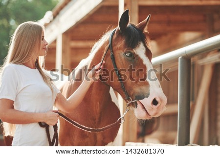 Calm animal. Happy woman with her horse on the ranch at daytime.