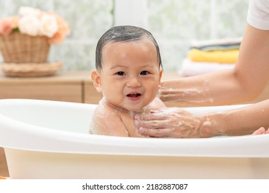 Calm Asian Baby Bathing In Bathtub Enjoy Laughing. Mother Bathing Her Son In Warm Water.Happy Adorable Newborn Infant Smile In Tub Relax And Comfortable Good Moment With Mom. Newborn Baby Care Concept