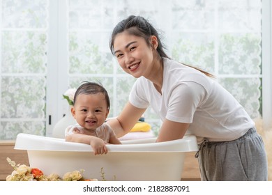 Calm Asian Baby Bathing In Bathtub Enjoy Laughing. Mother Bathing Her Son In Warm Water.Happy Adorable Newborn Infant Smile In Tub Relax And Comfortable Good Moment With Mom. Newborn Baby Care Concept