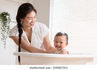 Calm asian baby bathing in bathtub enjoy laughing. mother bathing her son in warm water.Happy adorable newborn infant smile in tub relax and comfortable good moment with mom. Newborn baby care concept