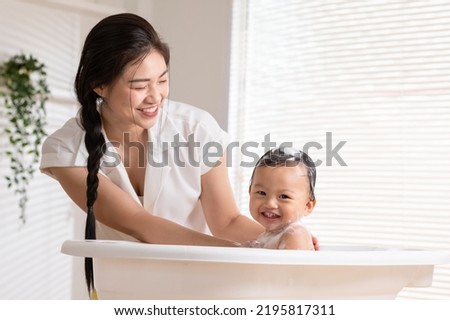 Calm asian baby bathing in bathtub enjoy laughing. mother bathing her son in warm water.Happy adorable newborn infant smile in tub relax and comfortable good moment with mom. Newborn baby care concept
