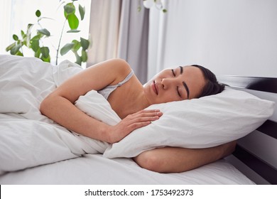 Calm Asian Woman Sleeping Sweetly In Bed Embracing Her Pillow While New Day Is Beginning